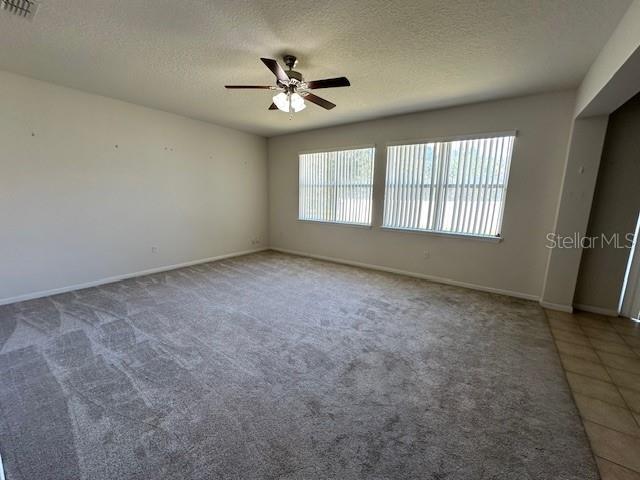 A spacious living room features neutral carpeting, a ceiling fan, and large windows with blinds — 236 BAYBERRY LAKES BOULEVARD, DAYTONA BEACH, FL