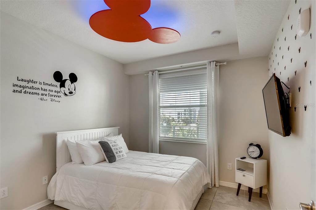 A bedroom features a white bed, a Mickey Mouse ceiling light, and a wall decal — 4731 CLOCK TOWER DRIVE UNIT 203, KISSIMMEE, FL