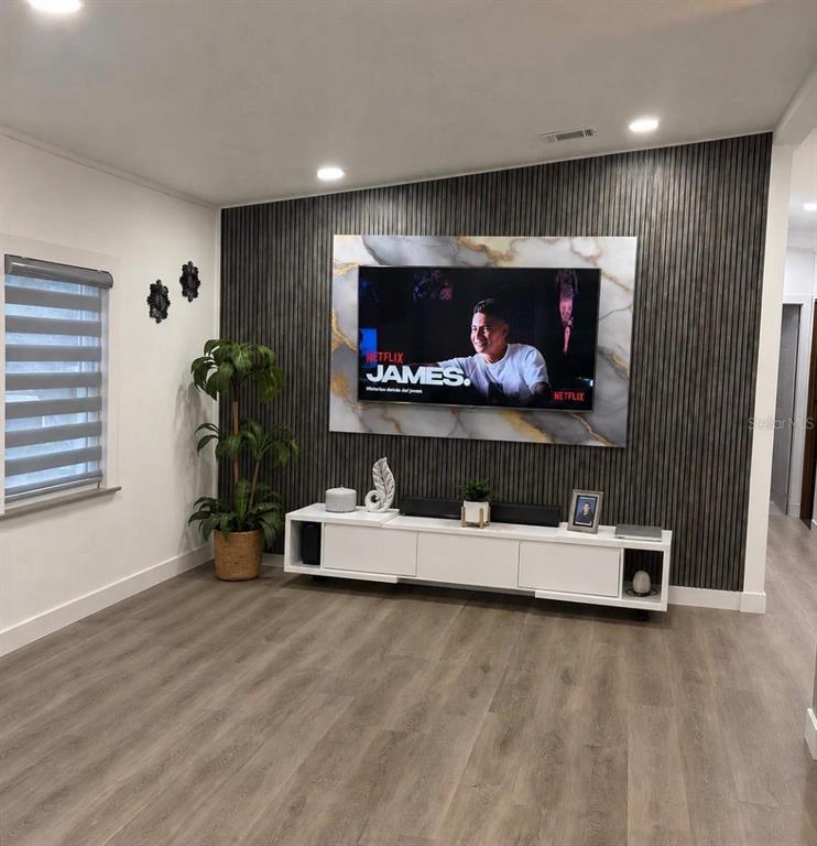 A living room features a wall-mounted television on a marble panel over wood slat paneling — 4 EDEN CEMETERY ROAD, FROSTPROOF, FL