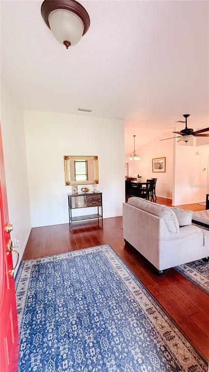 An entryway with a blue patterned rug, hardwood floors, and a console table with mirror — 898 CRITTENDEN AVENUE, ORANGE CITY, FL