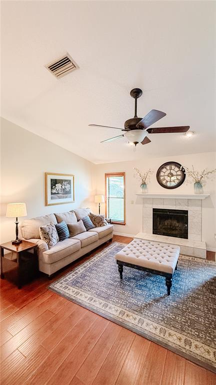 A living room features a beige sofa, a tufted ottoman, a fireplace, and hardwood floors — 898 CRITTENDEN AVENUE, ORANGE CITY, FL