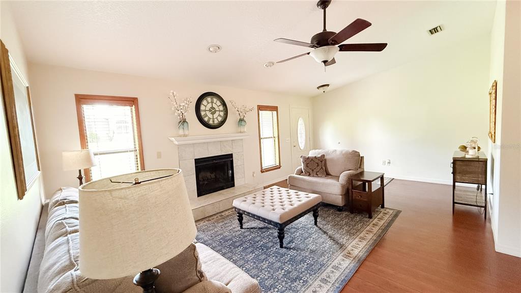 A living room features a fireplace, a ceiling fan, and a patterned area rug — 898 CRITTENDEN AVENUE, ORANGE CITY, FL