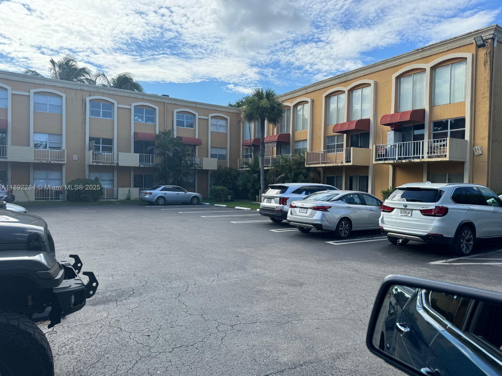 A multi-story apartment building with a parking lot in the foreground — 18101 NW 68th Ave # D207, Hialeah FL 33015, HIALEAH, FL