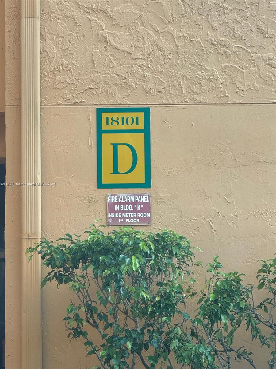 A building exterior wall features a green sign labeled 18101 D and a fire alarm notice — 18101 NW 68th Ave # D207, Hialeah FL 33015, HIALEAH, FL