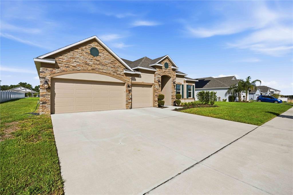 A single-story house with a stone facade, two-car garage, and a concrete driveway — 925 FIELDSTONE WAY, HAINES CITY, FL
