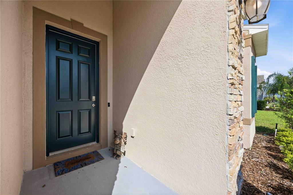 A dark green front door with a welcome mat and a small moose statue — 925 FIELDSTONE WAY, HAINES CITY, FL