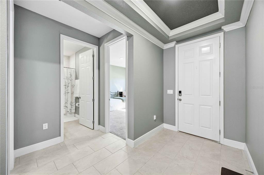 A tiled entryway features gray walls, a white door, and two doorways leading to rooms — 925 FIELDSTONE WAY, HAINES CITY, FL