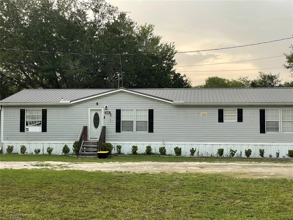 A single-story manufactured home with light gray siding, a metal roof, and black shutters — 8890 SE 66TH CIRCLE, TRENTON, FL