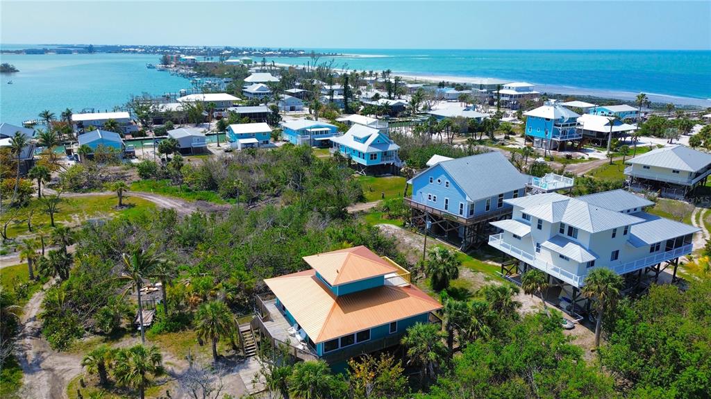 An aerial view of several elevated coastal houses surrounded by lush vegetation near the ocean — 9580 ALMIRATE COURT, PLACIDA, FL