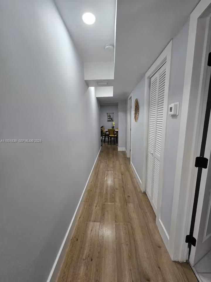 A hallway with light gray walls and wood-look flooring leads toward a dining area — 845 NW 3rd St # B, Miami FL 33128, MIAMI, FL