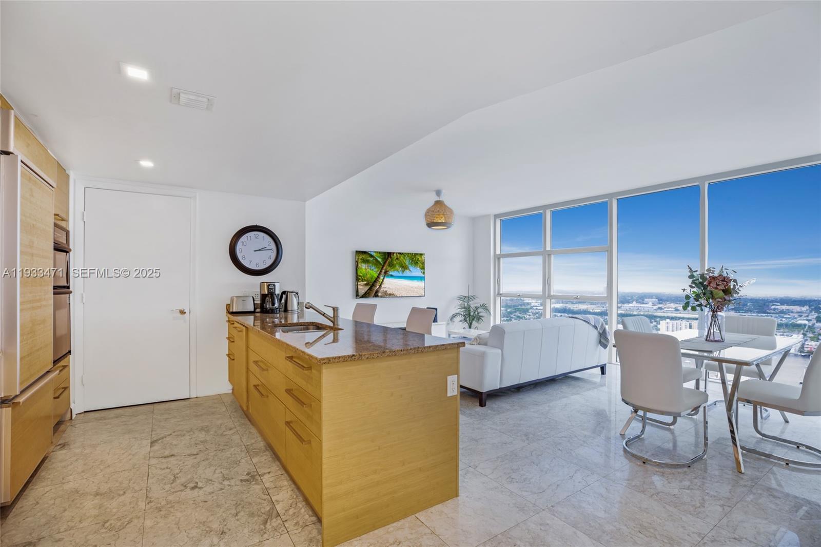 A modern kitchen island with granite countertops sits in an open-concept living area with floor-to-ceiling windows — 1830 S Ocean Dr # 4707, Hallandale Beach FL 33009, HALLANDALE BEACH, FL