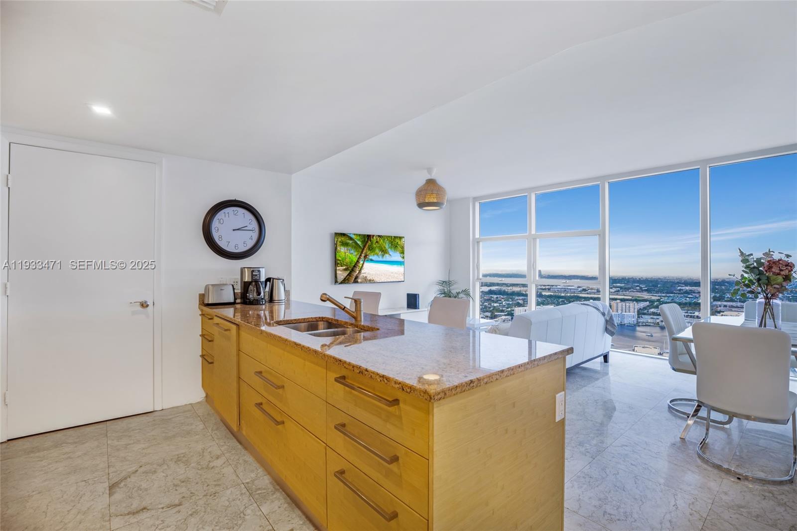 A kitchen island with granite countertops sits in an open-concept room with floor-to-ceiling windows — 1830 S Ocean Dr # 4707, Hallandale Beach FL 33009, HALLANDALE BEACH, FL