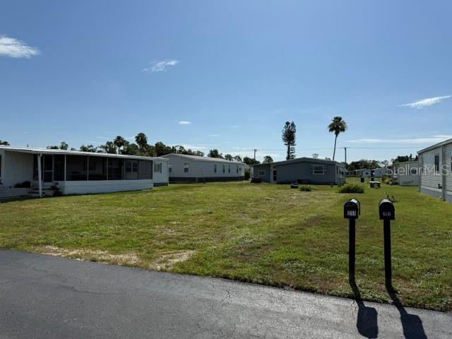 A vacant grassy lot sits between two mobile homes under a clear blue sky — 207 LA ROSAS, NORTH PORT, FL