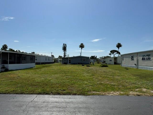 A vacant grassy lot sits between two manufactured homes under a clear blue sky — 207 LA ROSAS, NORTH PORT, FL