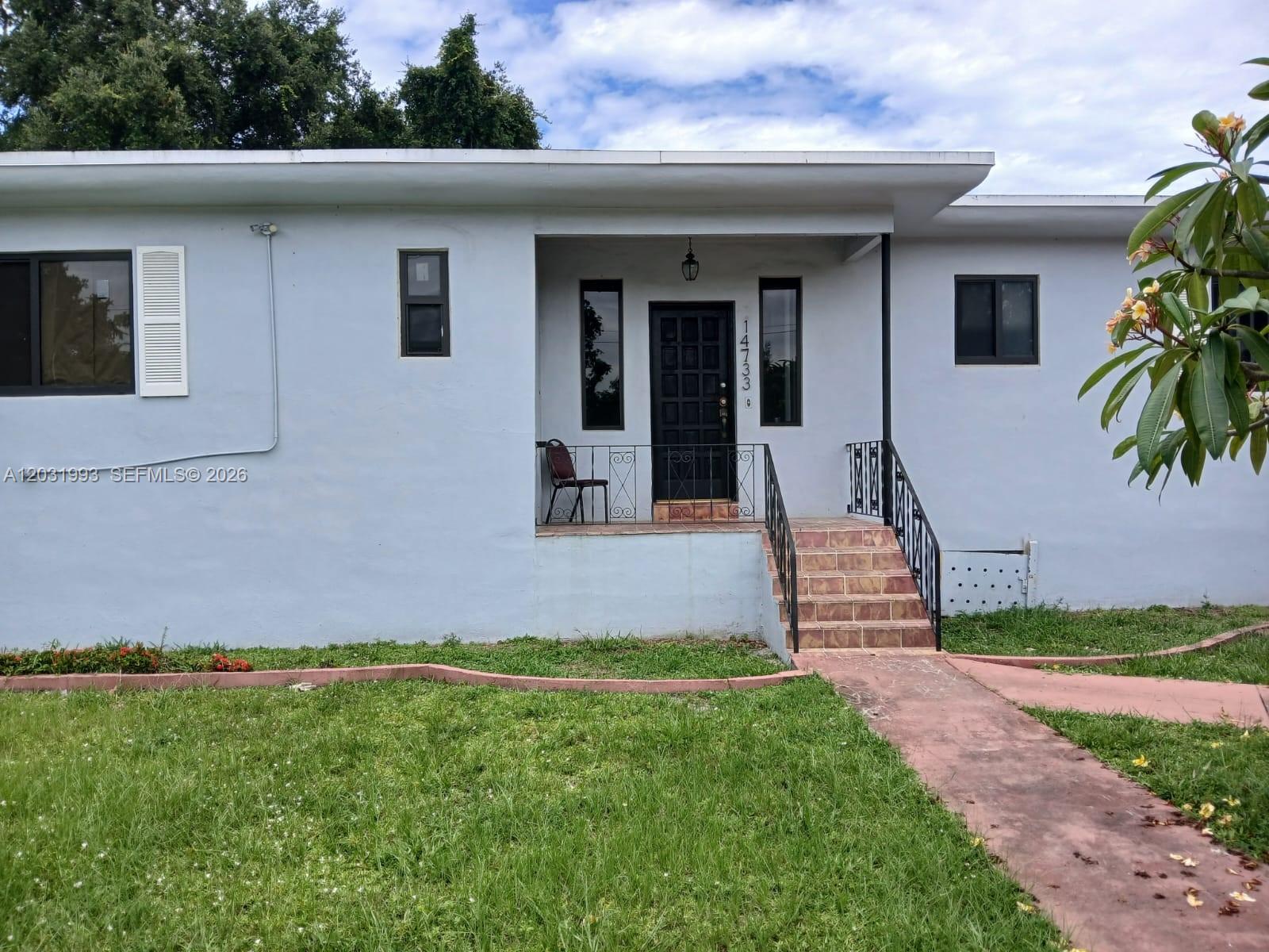 A light blue single-story house features a covered front porch with black iron railings — 1400 NE 148th St # 2, Miami FL 33161, MIAMI, FL