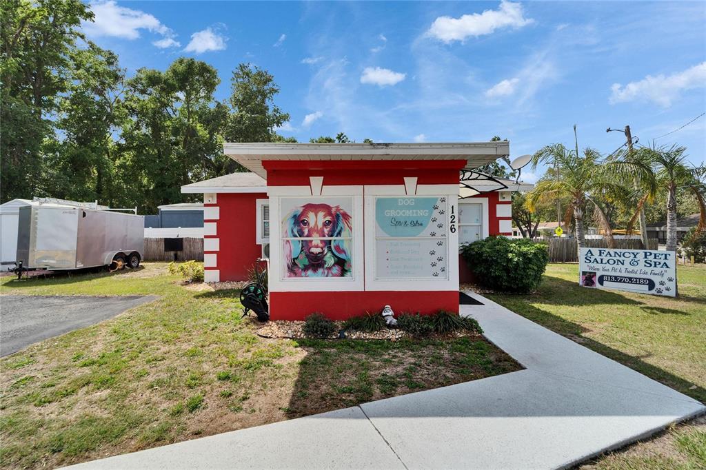 A red and white building with a dog grooming sign stands on a grassy lot — 126 RIDGEWOOD AVENUE, BRANDON, FL