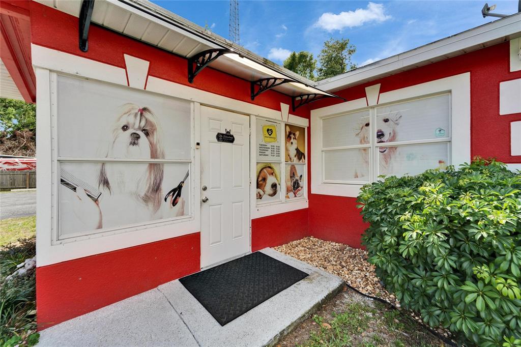 The exterior of a red building features a white door, dog-themed window decals, and awnings — 126 RIDGEWOOD AVENUE, BRANDON, FL