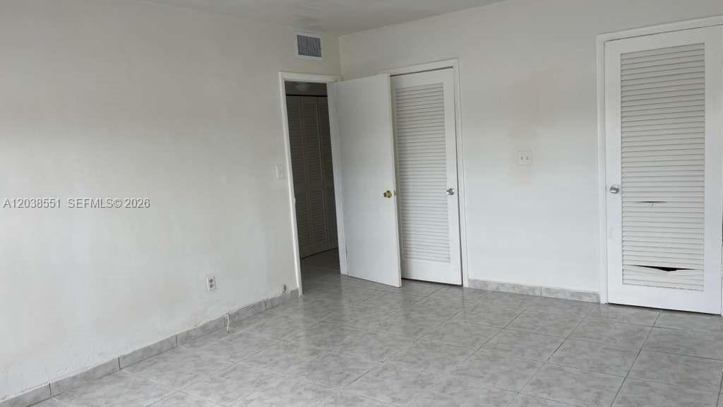 A room with white walls, tiled flooring, and two louvered closet doors — 1855 NE 121st St # 2, North Miami FL 33181, NORTH MIAMI, FL