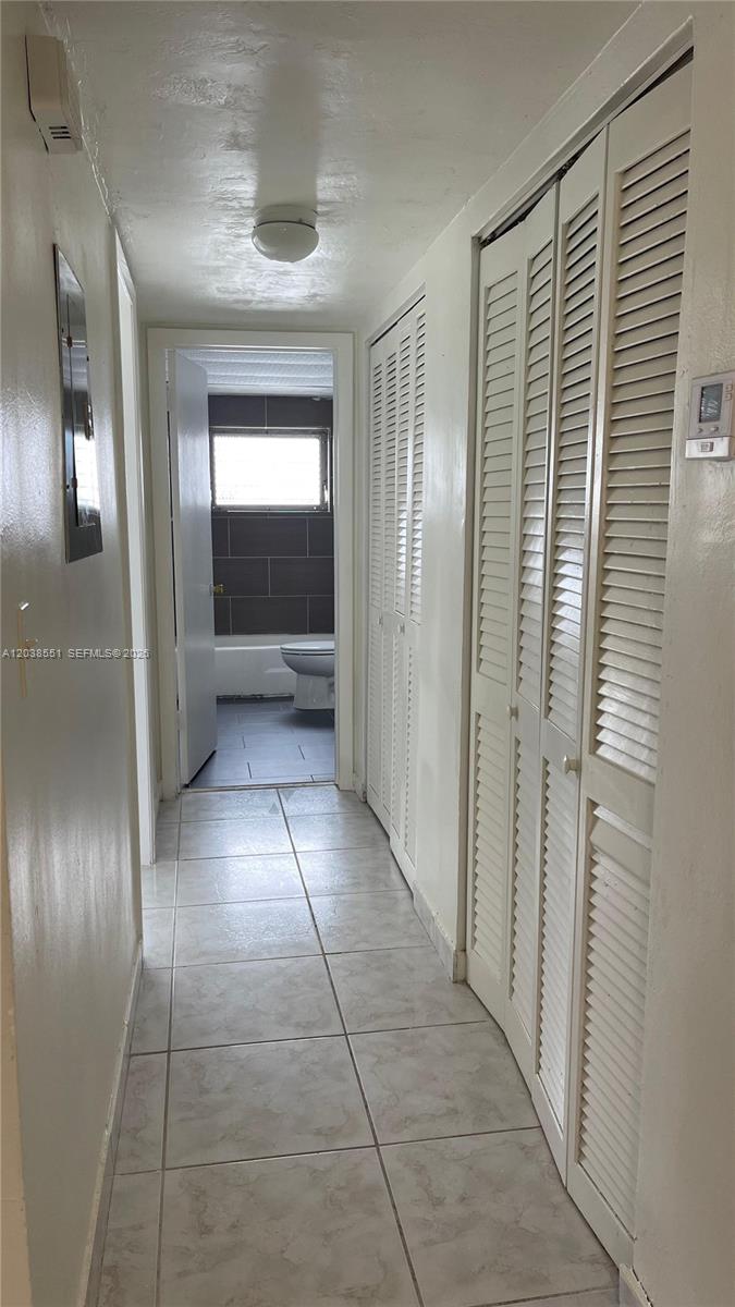 A hallway with tile flooring leads to a bathroom with a toilet and tub — 1855 NE 121st St # 2, North Miami FL 33181, NORTH MIAMI, FL