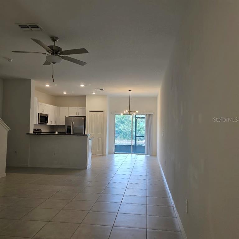An open-concept living area features a kitchen with white cabinets, tile flooring, and sliding doors — 6076 SHINER STREET, LAND O LAKES, FL