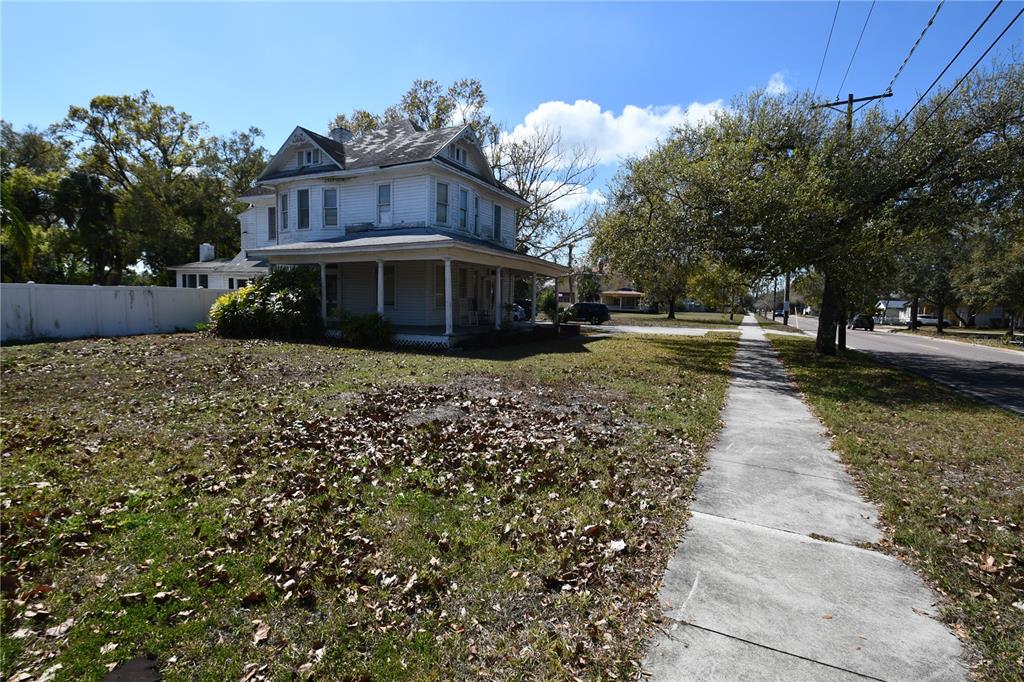A two-story white house with a wrap-around porch sits on a grassy corner lot — 8020 INTERBAY BOULEVARD, TAMPA, FL