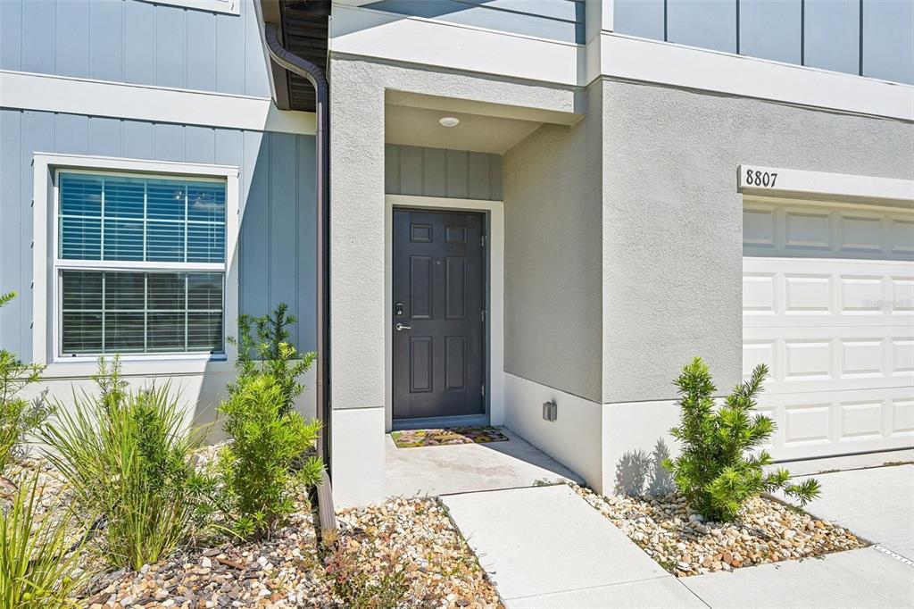 A two-story house with light blue vertical siding, a gray stucco lower level, and a garage — 8807 SUNSET PARK TRAIL, PARRISH, FL