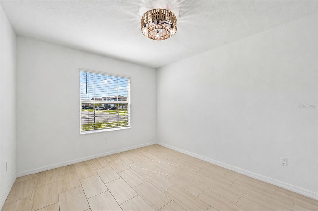 A home office with a desk and chair sits adjacent to a living area — 8807 SUNSET PARK TRAIL, PARRISH, FL