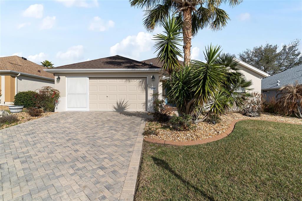 A single-story house with a paved driveway, a two-car garage, and a palm tree — 12747 SE 97TH TERRACE ROAD, SUMMERFIELD, FL