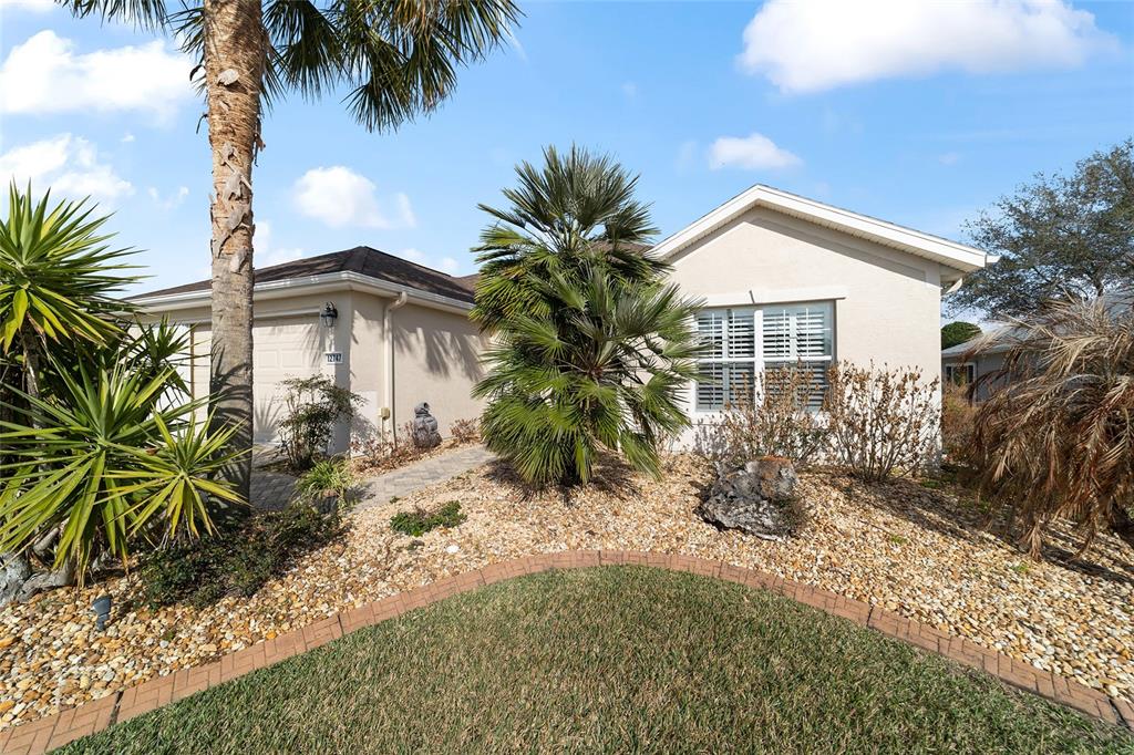 A single-story house with a beige stucco exterior, a garage, and a landscaped front yard — 12747 SE 97TH TERRACE ROAD, SUMMERFIELD, FL