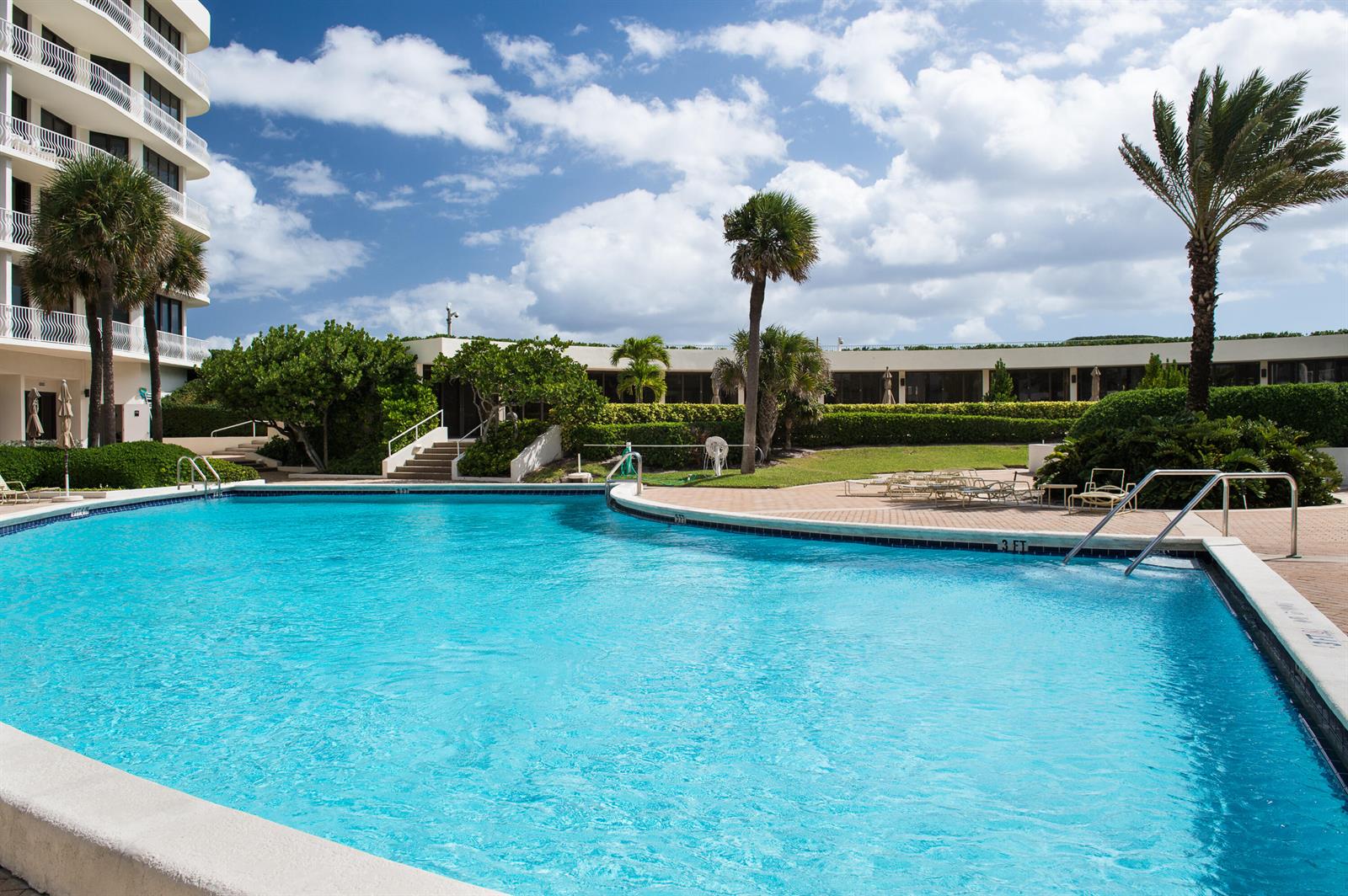 A swimming pool sits in front of a multi-story building with palm trees and landscaping — 2000 S Ocean Boulevard # 308n, Palm Beach FL 33480, PALM BEACH, FL