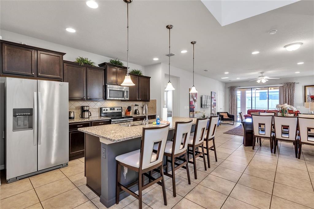A kitchen with dark cabinets, granite countertops, and a center island with bar seating — 8916 RHODES STREET, KISSIMMEE, FL