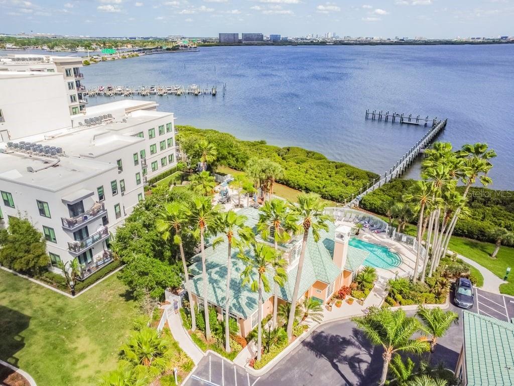 An aerial view shows a waterfront apartment building with a pool, palm trees, and pier — 4304 BAY CLUB CIRCLE UNIT 4304, TAMPA, FL