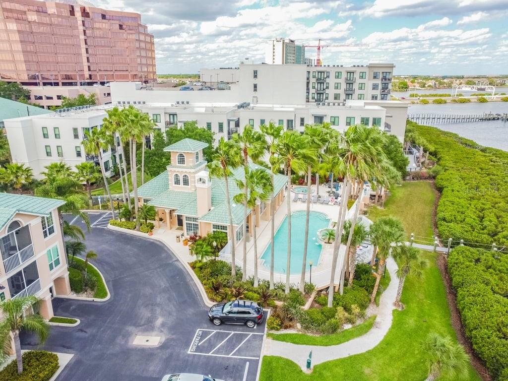 An aerial view shows a swimming pool, clubhouse, and parking area surrounded by palm trees — 4304 BAY CLUB CIRCLE UNIT 4304, TAMPA, FL