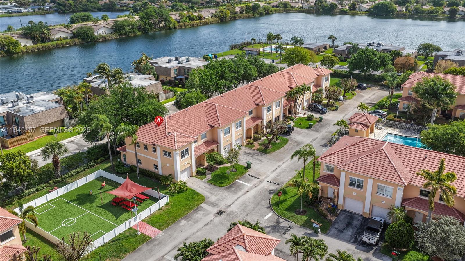 An aerial view shows a multi-unit residential complex with red-tiled roofs and a small soccer field — 501 Talia Circle, Palm Springs FL 33461, PALM SPRINGS, FL