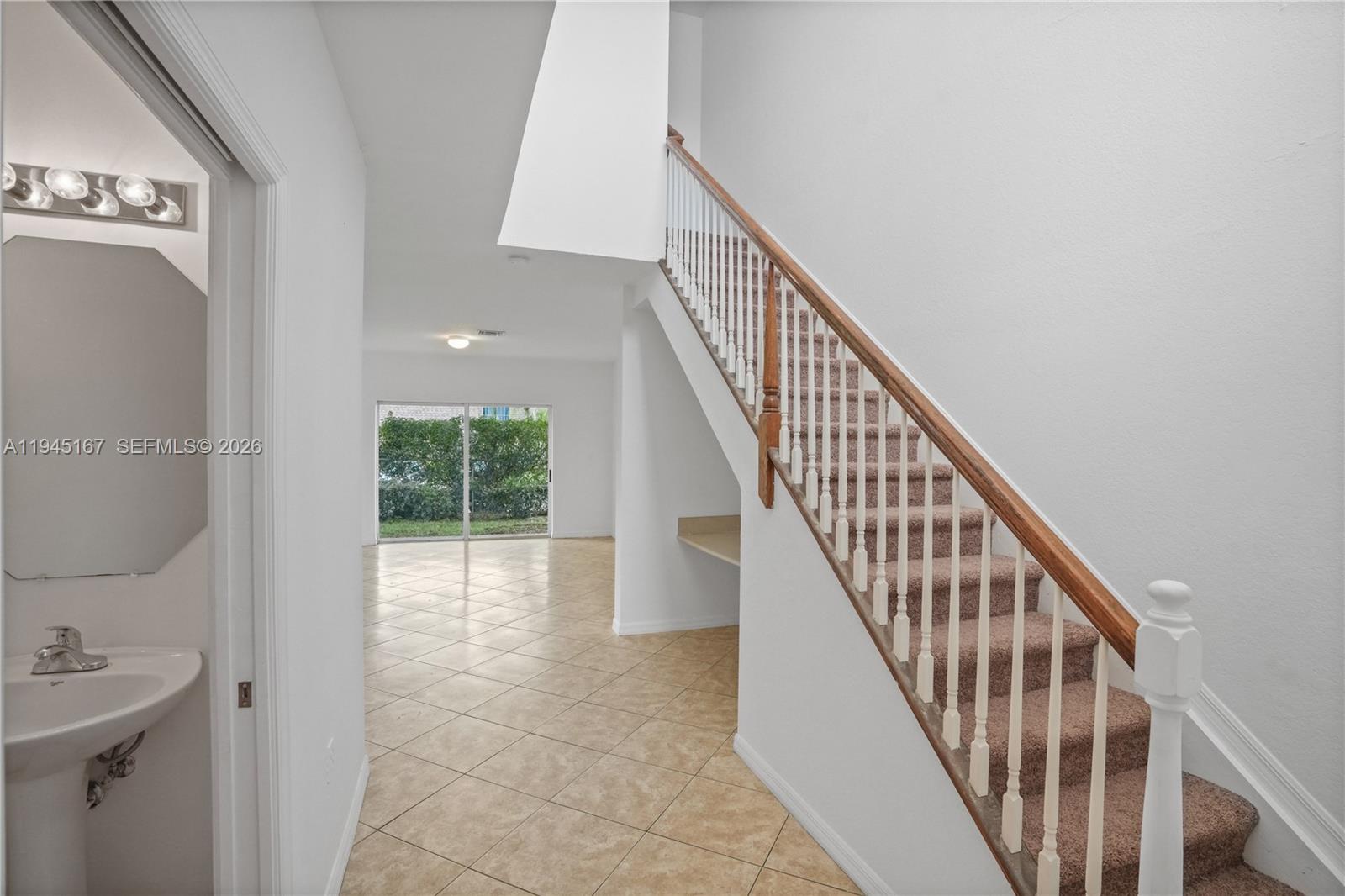 A tiled entryway features a half bathroom, a staircase with carpeted steps, and a living area — 501 Talia Circle, Palm Springs FL 33461, PALM SPRINGS, FL