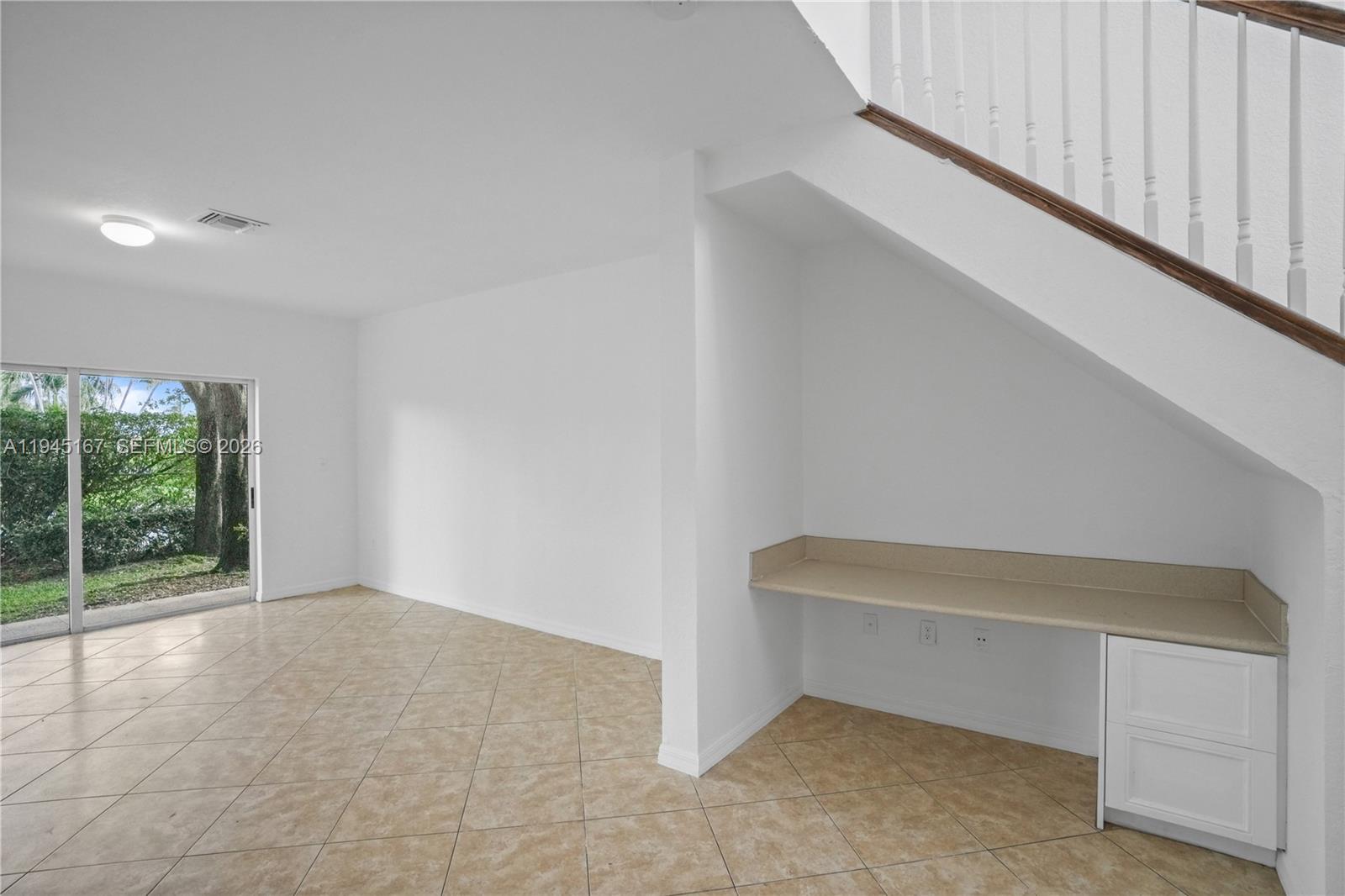 A room with tile flooring, a sliding glass door, and a built-in desk under stairs — 501 Talia Circle, Palm Springs FL 33461, PALM SPRINGS, FL