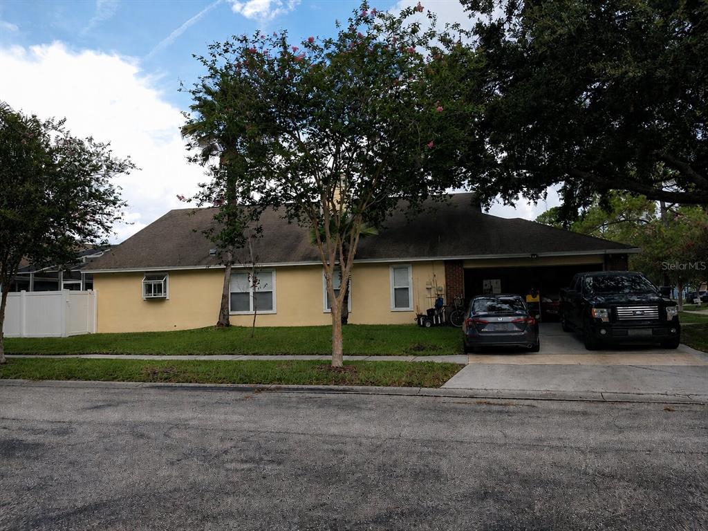 A yellow single-story house with a two-car garage and a driveway in front — 17502 WOODTHRUSH PLACE, TAMPA, FL
