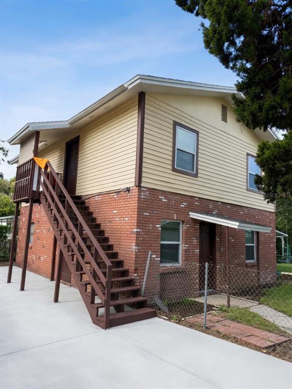 A two-story building with a brick lower level, yellow siding, and an exterior wooden staircase — 3356 AVENUE Q NW, WINTER HAVEN, FL
