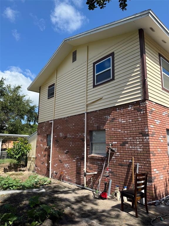 The exterior of a two-story house features yellow siding over a red brick base — 3356 AVENUE Q NW, WINTER HAVEN, FL