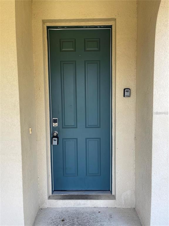 A dark green six-panel front door is set within a beige stucco entryway — 3129 TOCOA CIRCLE, KISSIMMEE, FL