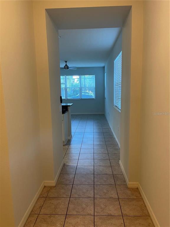 A tiled hallway leads into a kitchen area with a ceiling fan and large windows — 3129 TOCOA CIRCLE, KISSIMMEE, FL