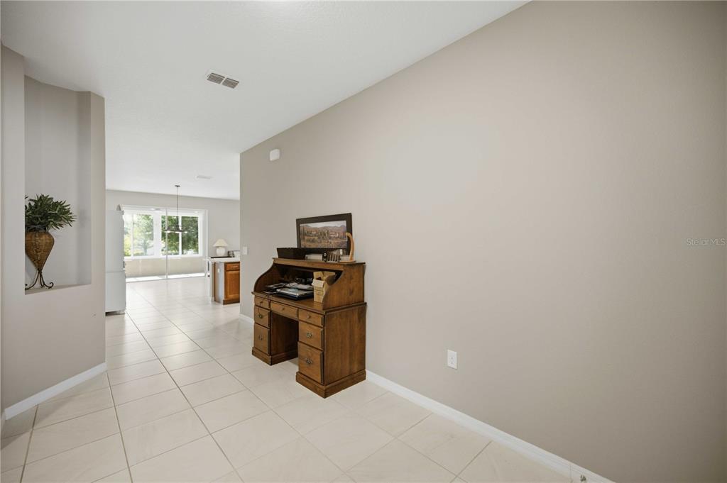 A wooden roll-top desk sits against a large beige wall in a tiled hallway — 8525 SW 79TH AVENUE, OCALA, FL