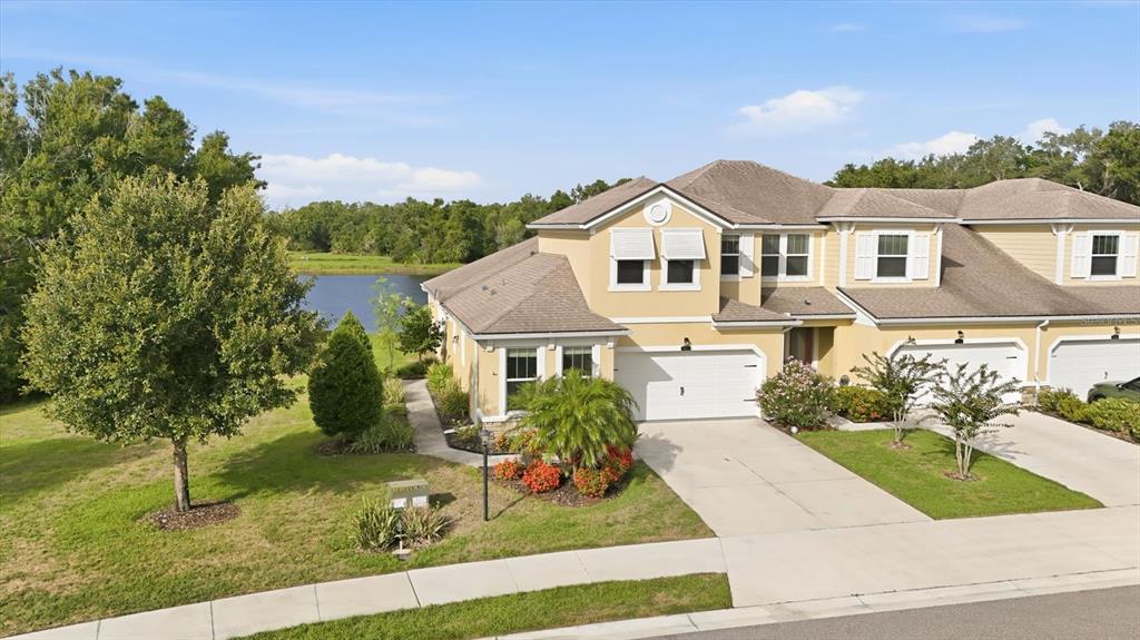 A two-story yellow house with a white garage door and a palm tree in front — 11474 ROLLING GREEN DRIVE, BRADENTON, FL