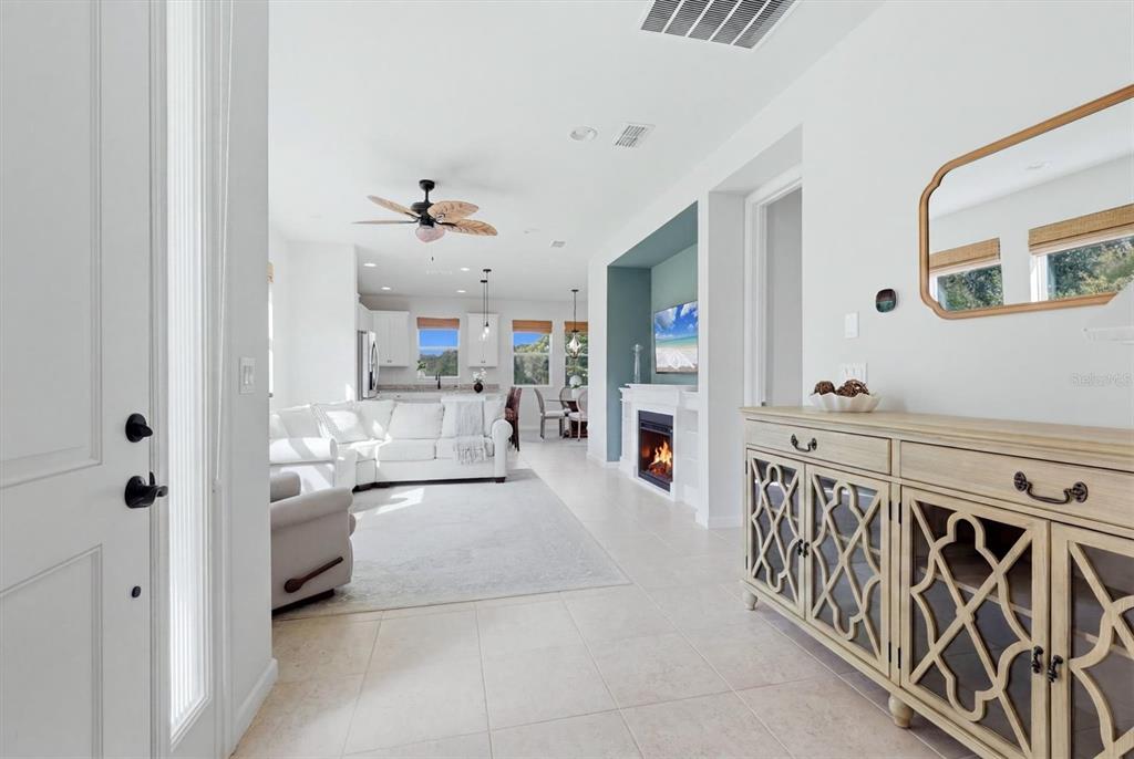 An entryway leads into an open-concept living room with a fireplace and a kitchen beyond — 11474 ROLLING GREEN DRIVE, BRADENTON, FL
