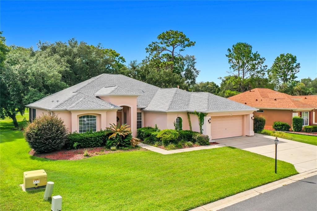 A single-story, light-pink house with a gray shingled roof and a two-car garage — 12992 SE 91ST COURT, SUMMERFIELD, FL