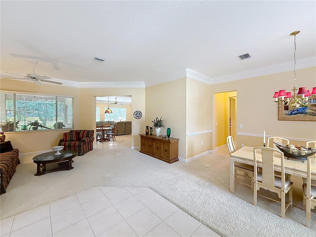 A living and dining area with beige walls, carpeted floors, and a tiled entryway — 12992 SE 91ST COURT, SUMMERFIELD, FL