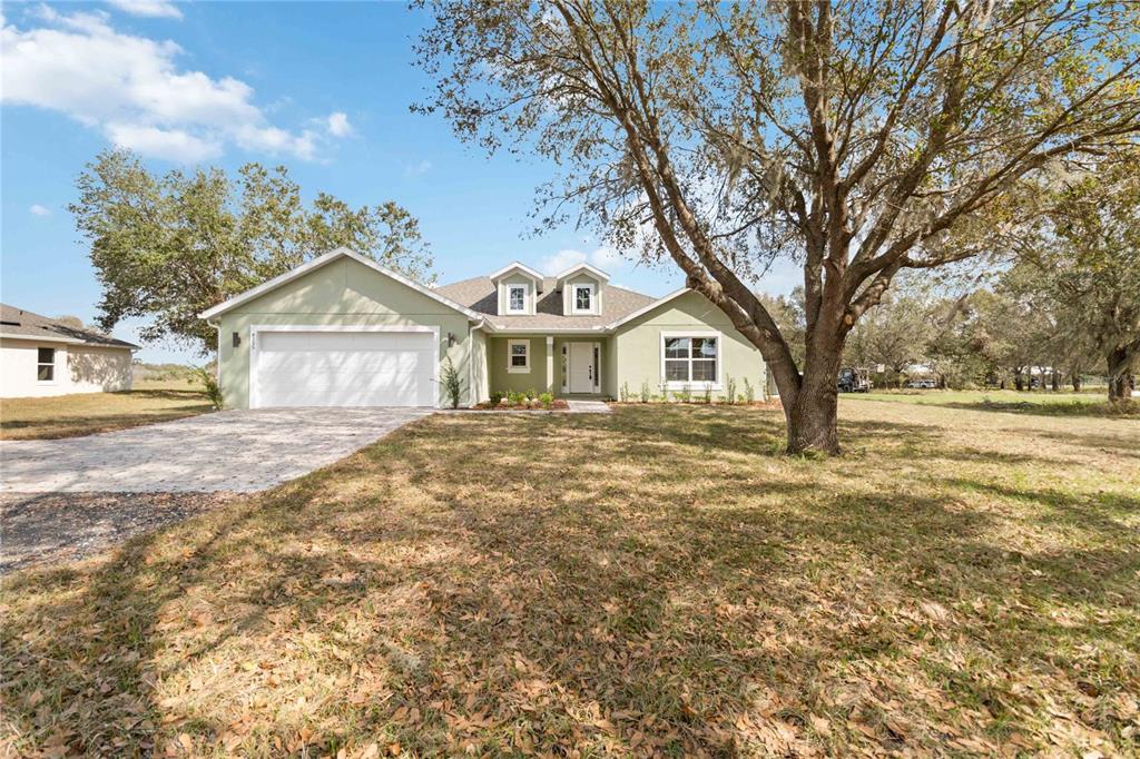 A light green single-story house with a two-car garage and a large front yard — 4255 TUCKER AVENUE, ST CLOUD, FL