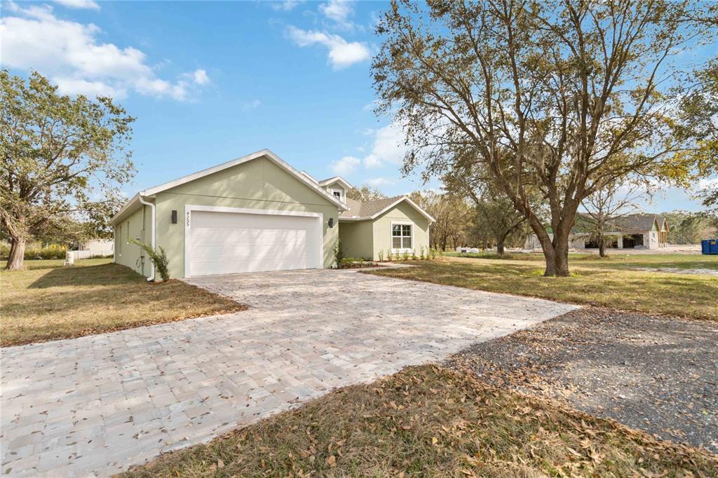 A light green single-story house with a white garage door and a paved driveway — 4255 TUCKER AVENUE, ST CLOUD, FL