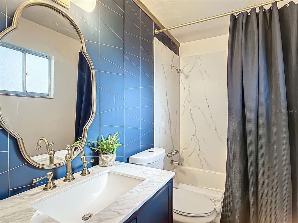 A bathroom features a marble-topped vanity, a blue tiled wall, and a white shower surround — 3729 SW 15 STREET, GAINESVILLE, FL