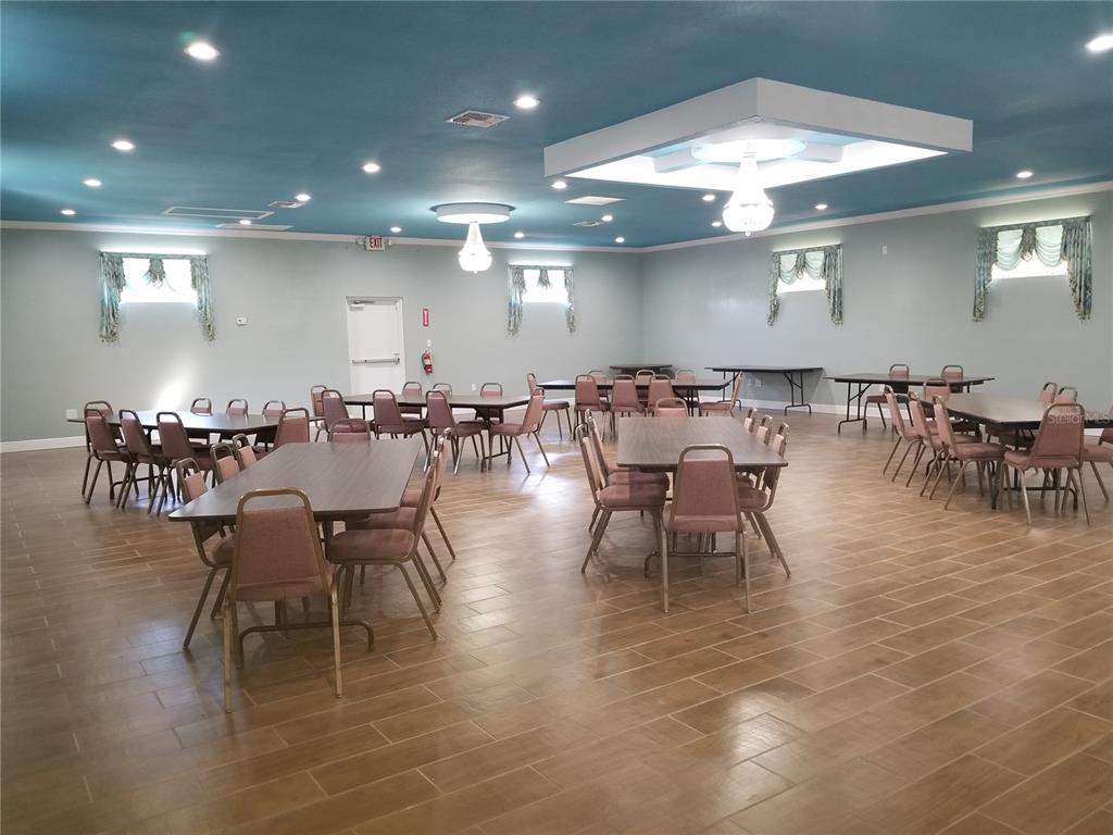 A large event hall features light blue walls, a blue ceiling, and wood-look tile flooring — 2240 MARCELLA WAY, LEESBURG, FL